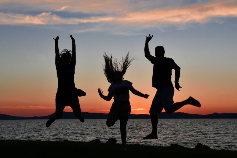 silhouette of three people jumping on the beach